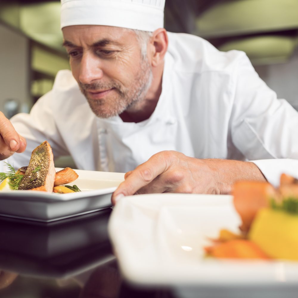 Closeup of a concentrated male chef garnishing food in the kitchen